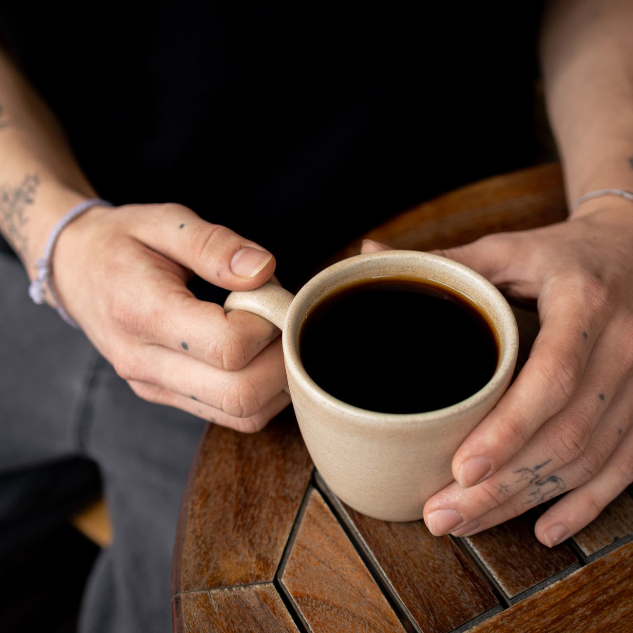 Pregnant woman holding a mug of decaf or tea — warm lighting, contemplative composition. Coffee cups arranged in front showing 'how much is safe' messaging.