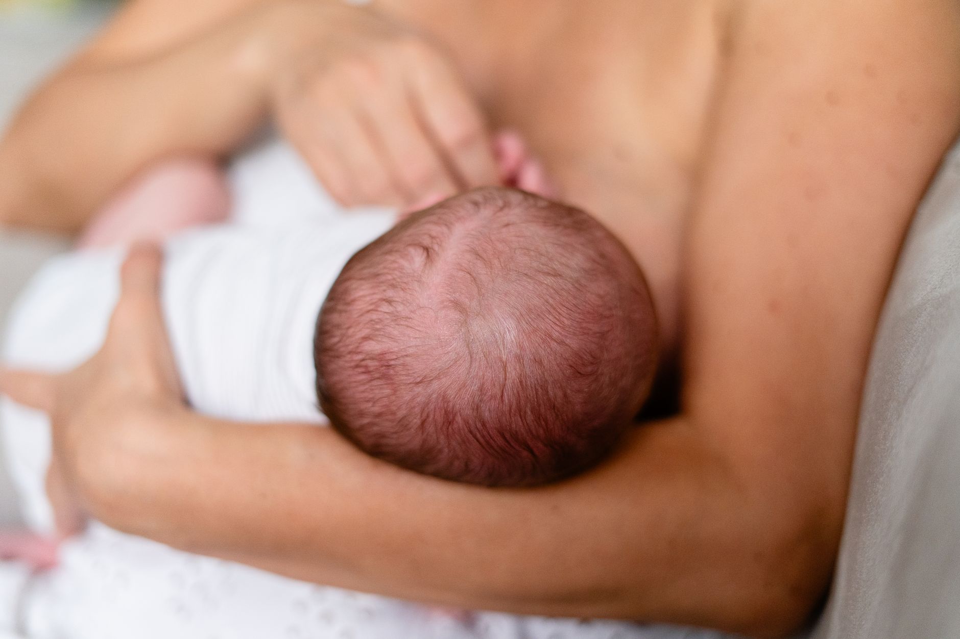 Postpartum mother breastfeeding her newborn while holding a warm mug of lactation tea, nourishing food nearby